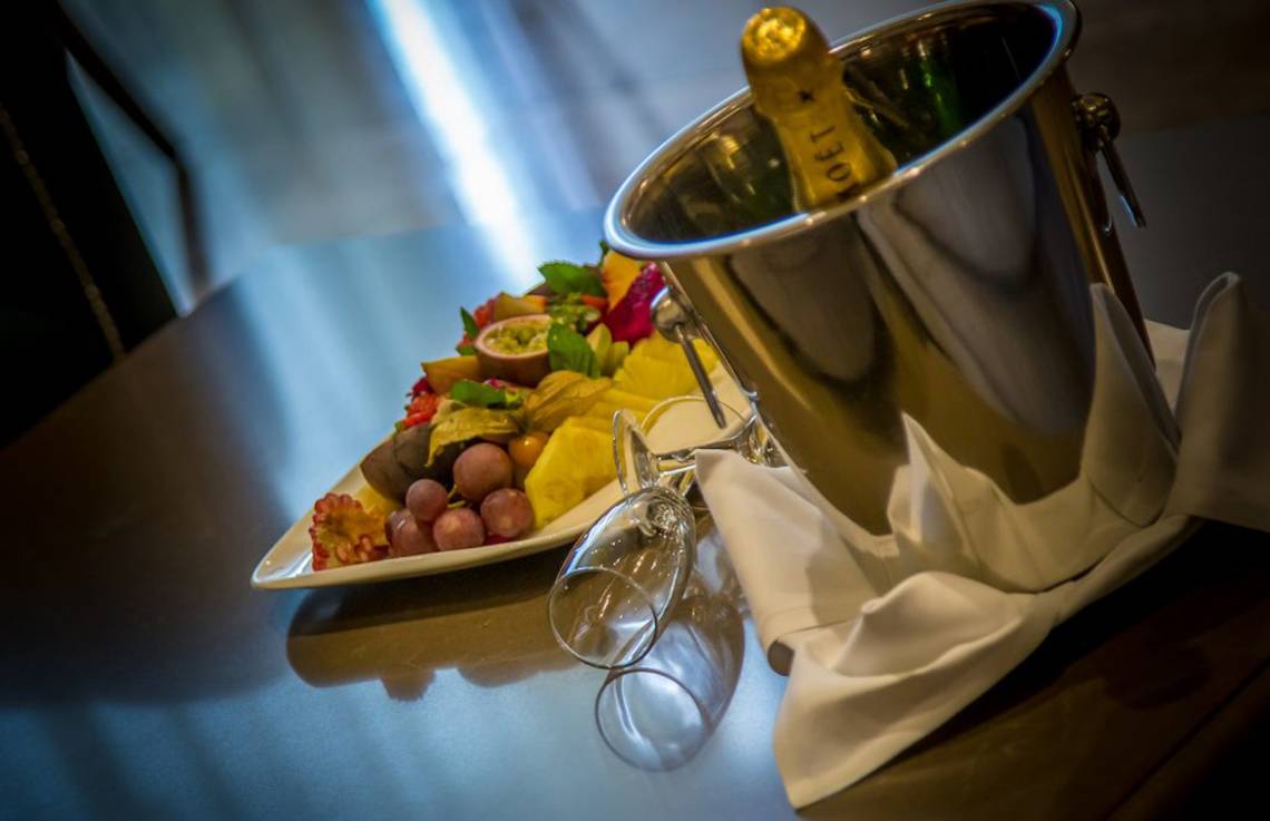 Eine Fruchtplatte und eine Flasche Champagner auf einem Tisch im Adams Beach Hotel.