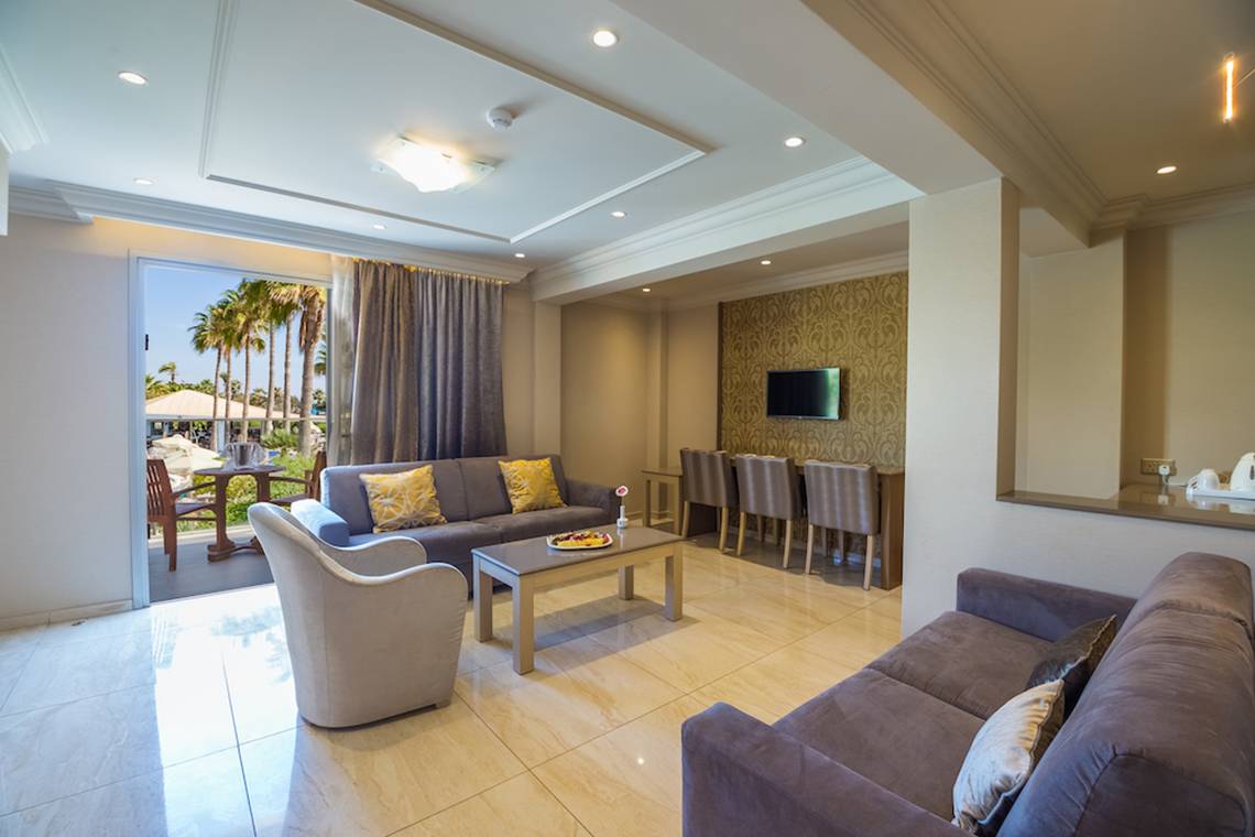 Wohnzimmer im Adams Beach Hotel mit zwei Sofas, einem Tisch und einem Fernseher.
