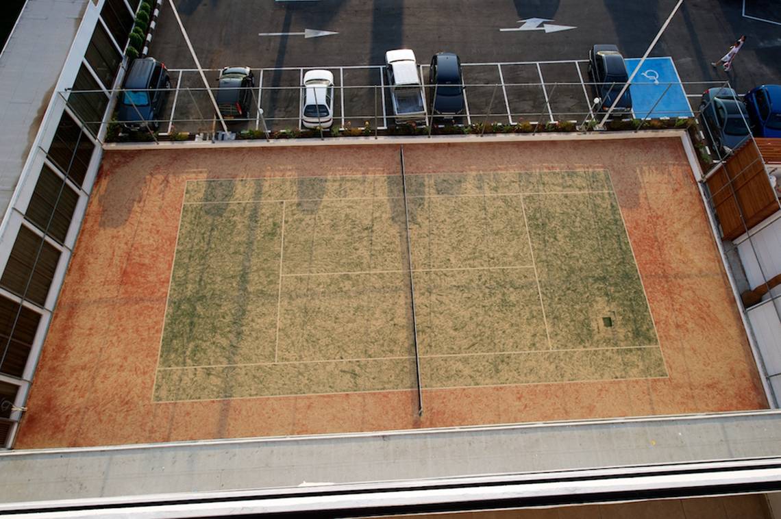 Oberirdischer Tennisplatz auf dem Dach des Adams Beach Hotels mit umliegenden Parkmöglichkeiten.