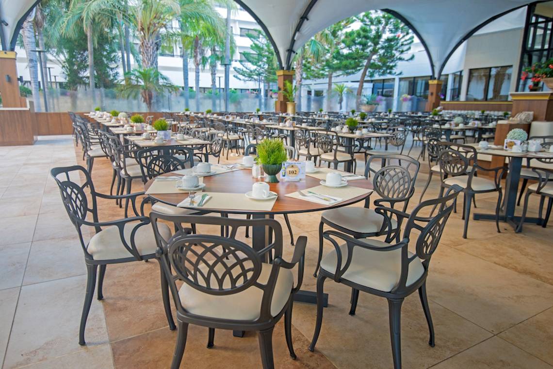 Innenbereich eines Restaurants im Adams Beach Hotel mit vielen runden Tischen und Stühlen.