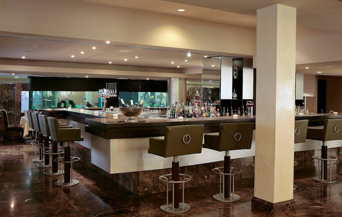 Barlounge im Adams Beach Hotel mit Barhockern und vielen Getränken.