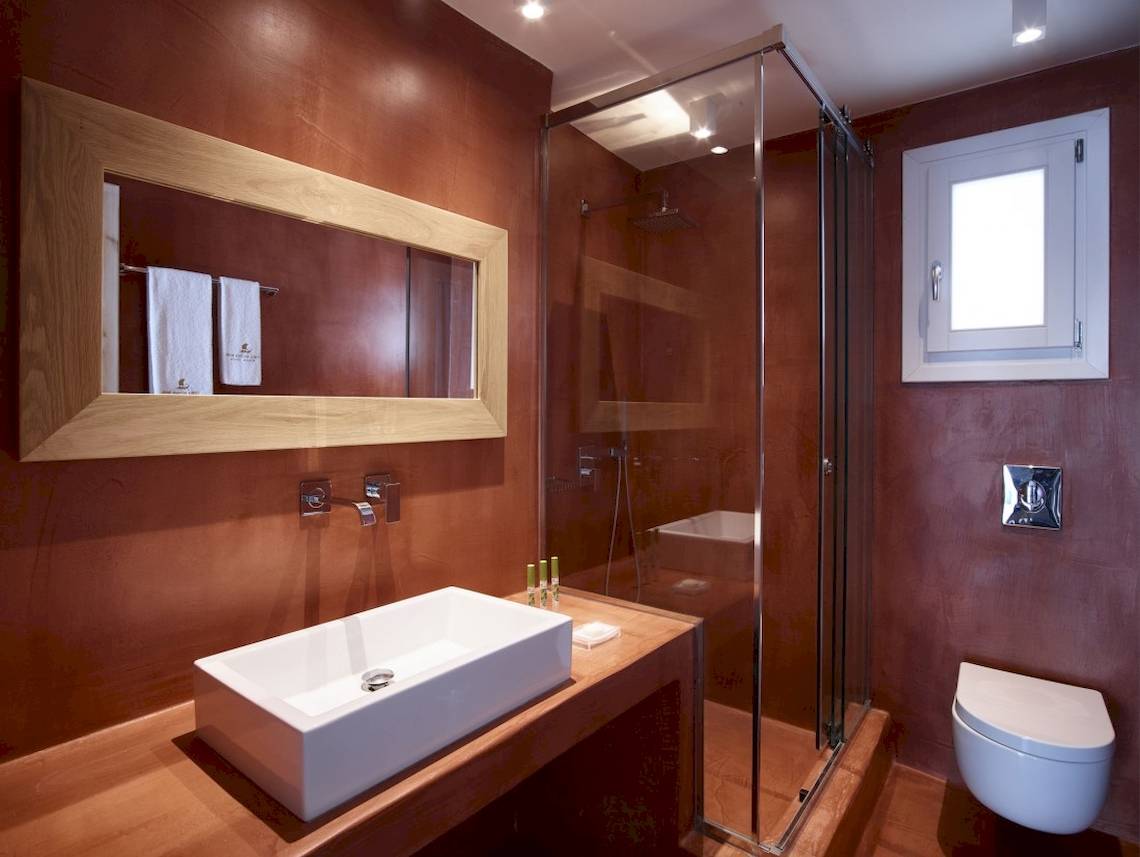 Ein Badezimmer im Vencia Boutique Hotel mit einem Waschbecken, einer Glasdusche und einem Toilettensitz.