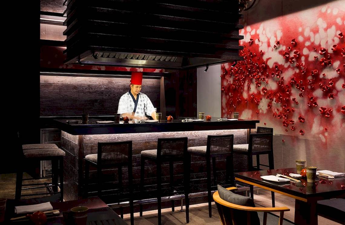 Restaurantbar im LUX South Ari Atoll mit rotem Hintergrund und einem Koch in traditioneller Kleidung.