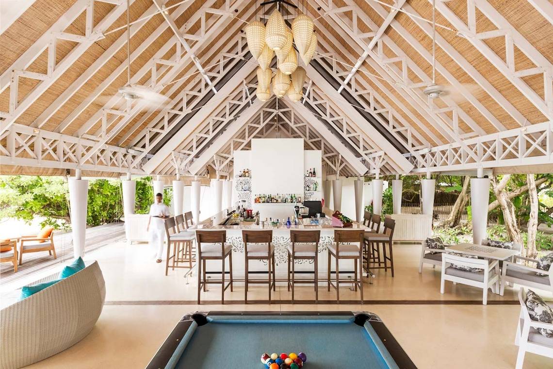 Innenansicht der Bar im LUX South Ari Atoll Hotel mit Pooltisch und hohen Holzstühlen.