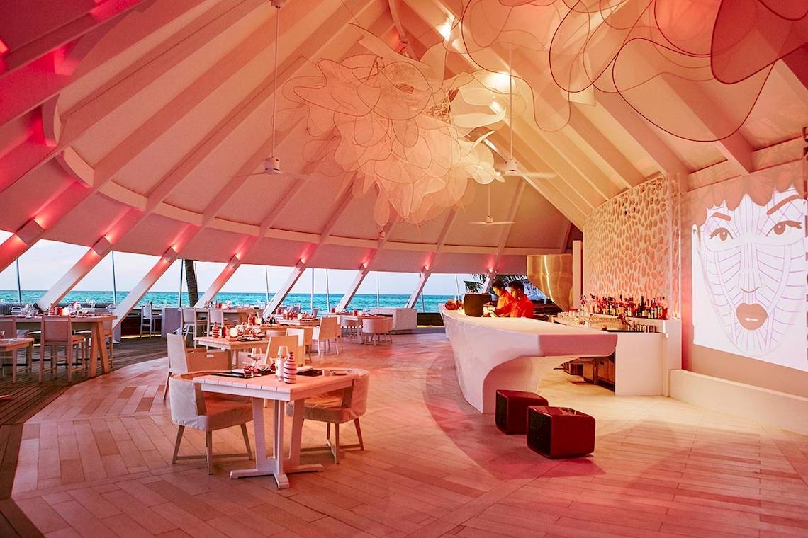 Innenansicht des Restaurants im LUX South Ari Atoll Hotel mit modernem Design, Holzboden und Blick auf das Meer.