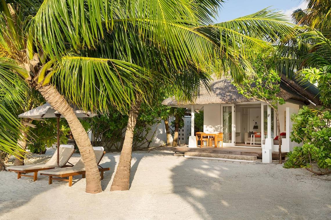 Strandvilla des LUX South Ari Atoll Hotels, umgeben von Palmen und Möbeln im Freien
