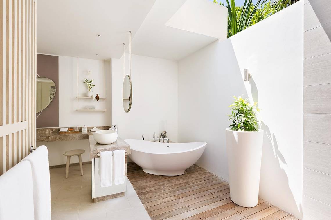 Modernes Badezimmer im LUX South Ari Atoll Hotel mit Badewanne, zwei Waschbecken und Holzboden.