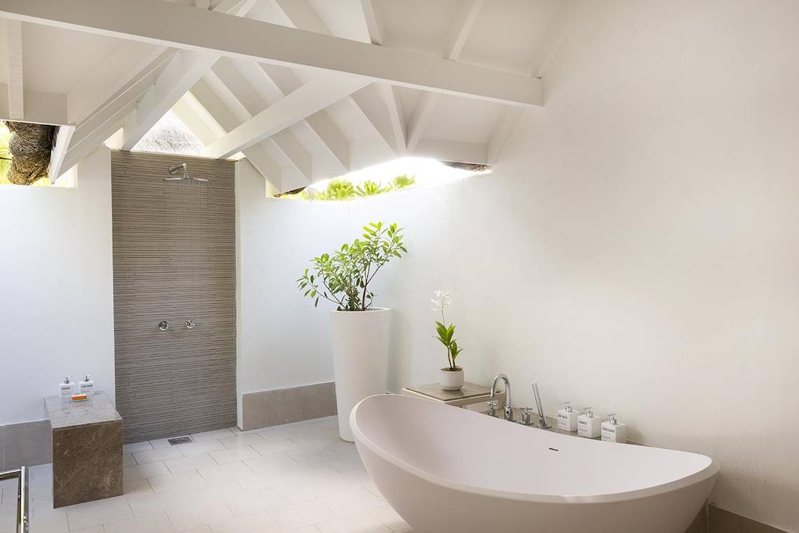 Luxuriöses Badezimmer im LUX South Ari Atoll Hotel mit Badewanne, Dusche und Pflanzen.
