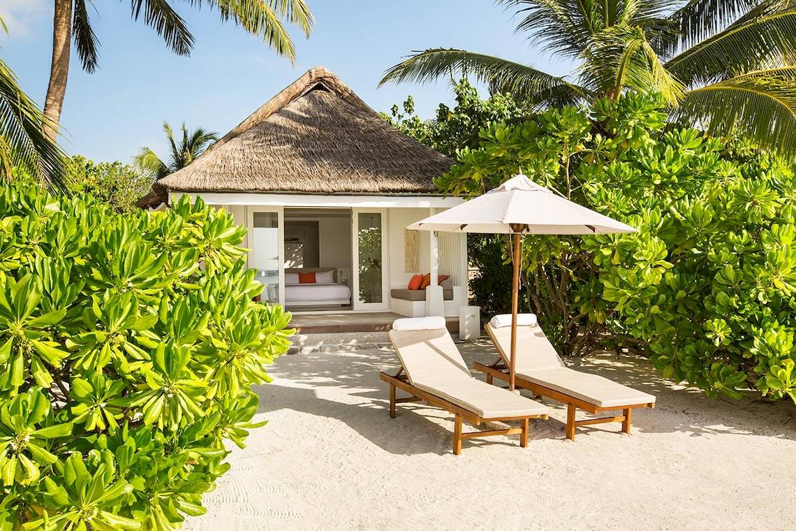 Strandhaus des LUX South Ari Atoll mit Sonnenliegen und einem Schirm