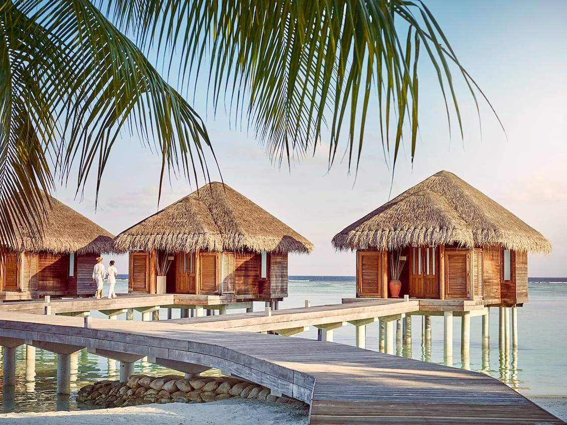 Drei traditionelle Hütten am Wasser im LUX South Ari Atoll Hotel.