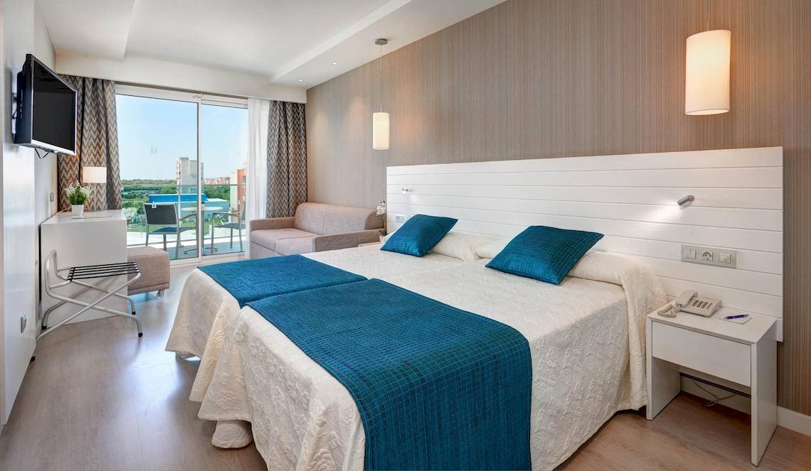 Doppelzimmer im Hipotels Said mit zwei Betten, blauen Kissen und Blick auf die Terrasse.