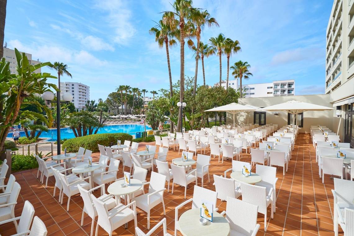 Terrasse mit weißen Tischen und Stühlen im Hipotels Said Hotel neben einem Pool