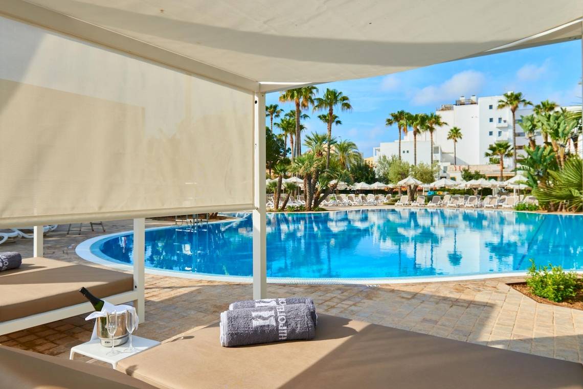 Außenbereich des Hipotels Said Hotels mit Swimmingpool und Liegestühlen.