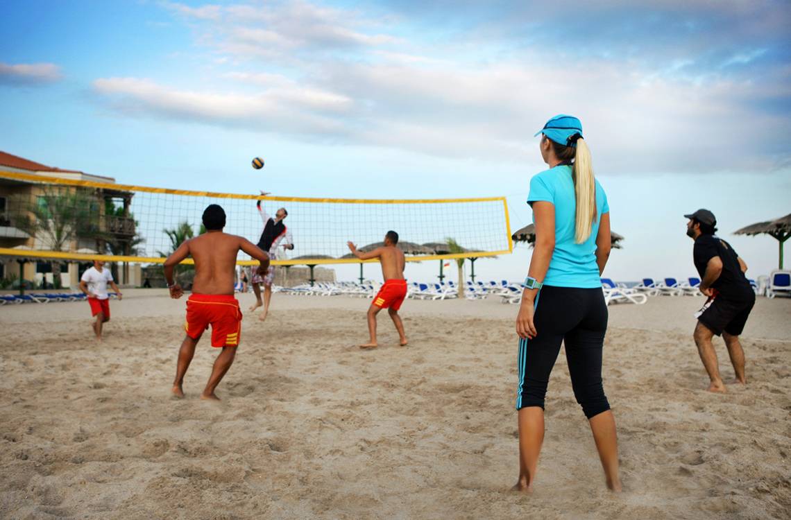 Gruppe von Menschen spielt Volleyball am Strand vor dem Fujairah Rotana Resort & Spa.