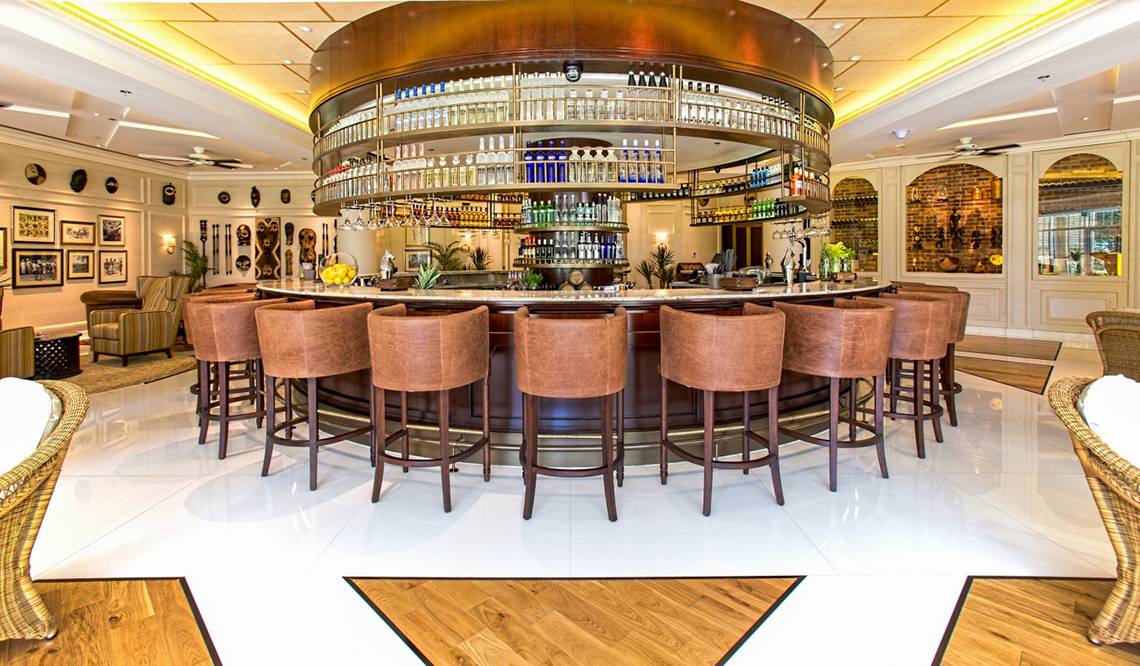Bar im Fujairah Rotana Resort & Spa mit vielen Flaschen und braunen Stühlen.