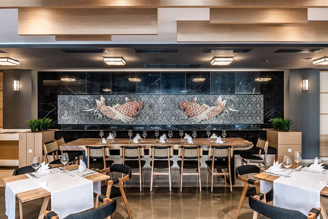 Innenbereich des Avra Imperial Hotel Restaurants mit Fischwand und gedeckten Tischen.