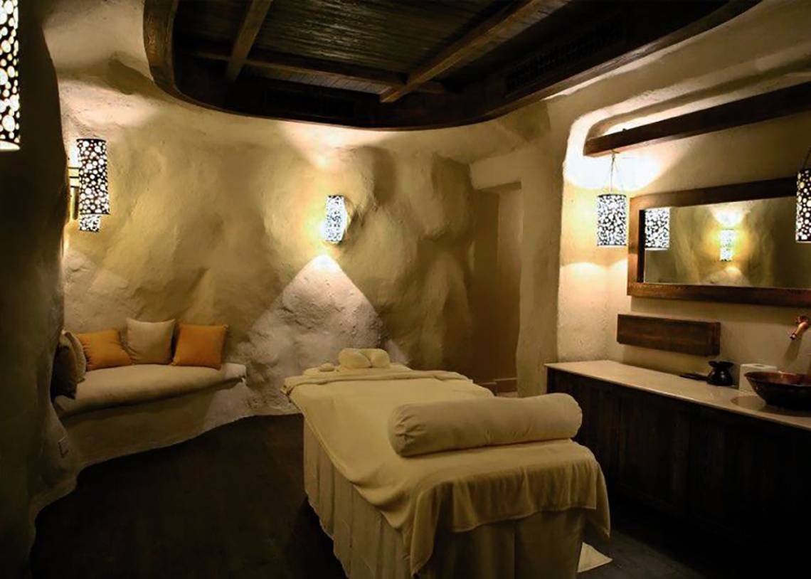 Behandlungsraum im Hotel Spa des Pickalbatros The Palace Port Ghalib mit Massageliege, Kissen, Wandleuchten und Spiegel.