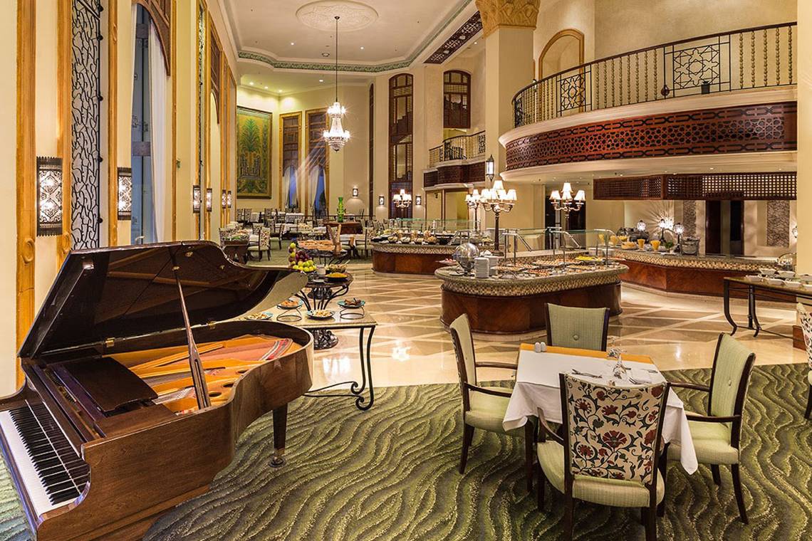 Innenbereich des Pickalbatros The Palace Port Ghalib Hotel mit Klavier, Tischen und Buffet.