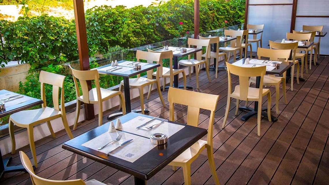Terrasse des Hersonissos Palace Hotels mit gedeckten Tischen und Stühle an einem sonnigen Tag.