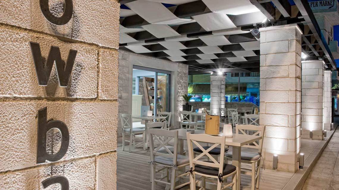 Außenbereich des Hersonissos Palace Hotels mit beleuchteten Säulen und Tischplätzen.
