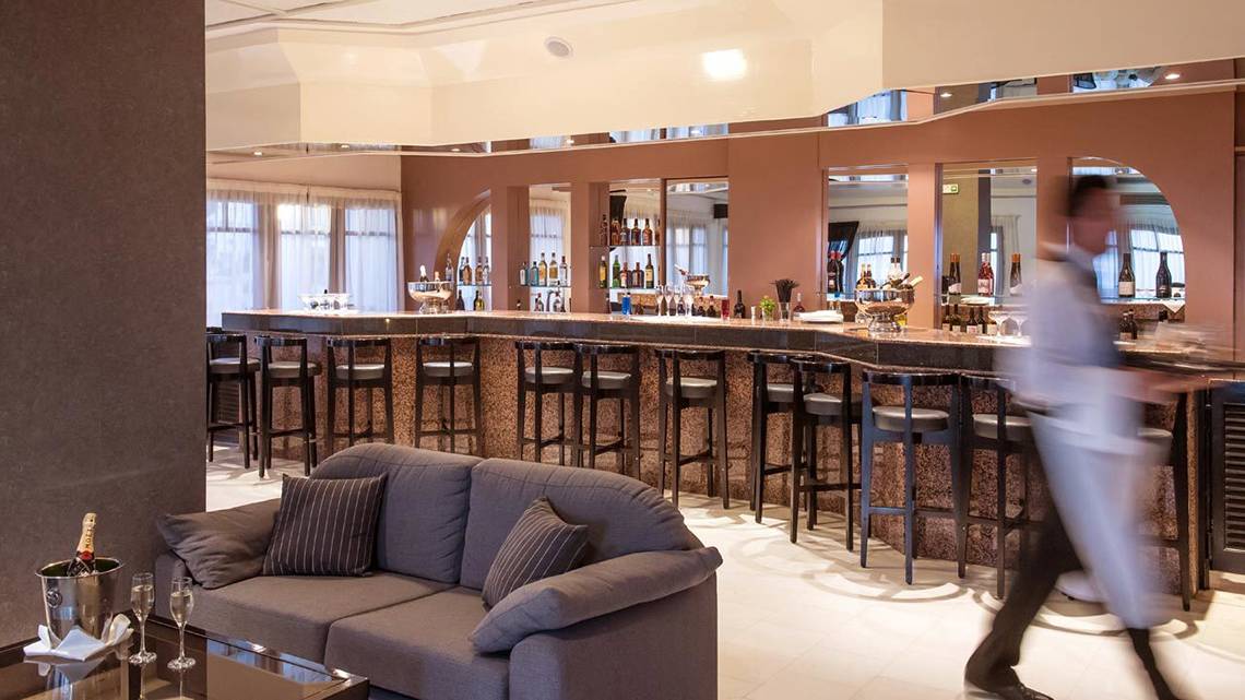 Barbereich des Hersonissos Palace Hotels mit Barhockern, einer Couch und einem Mitarbeiter