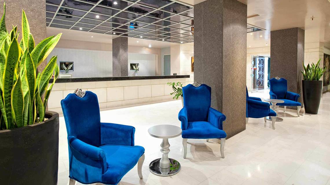 Lobby des Hersonissos Palace Hotels mit blauen Stühlen und weißen Tischen.