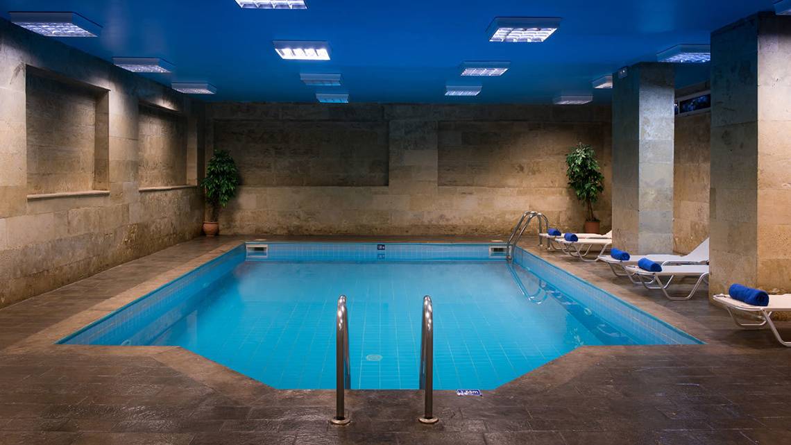 Innenpool im Hersonissos Palace Hotel mit blauen Kacheln und Lounge-Sesseln.