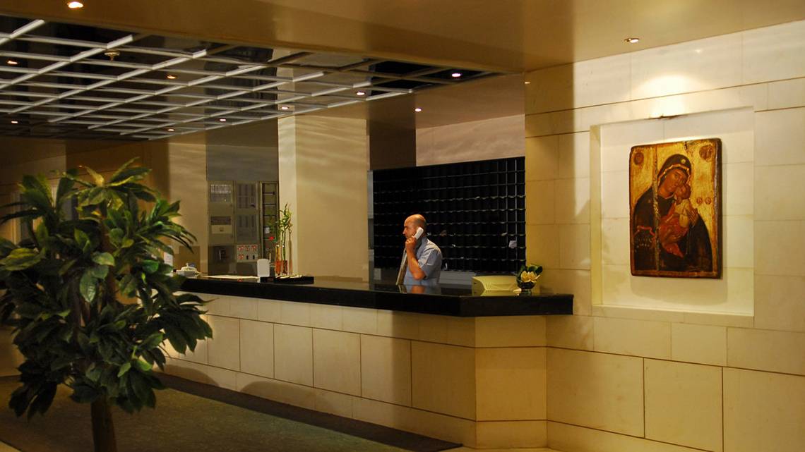 Mann telefoniert an der Rezeption des Hersonissos Palace Hotels, wo eine Ikone an der Wand hängt.