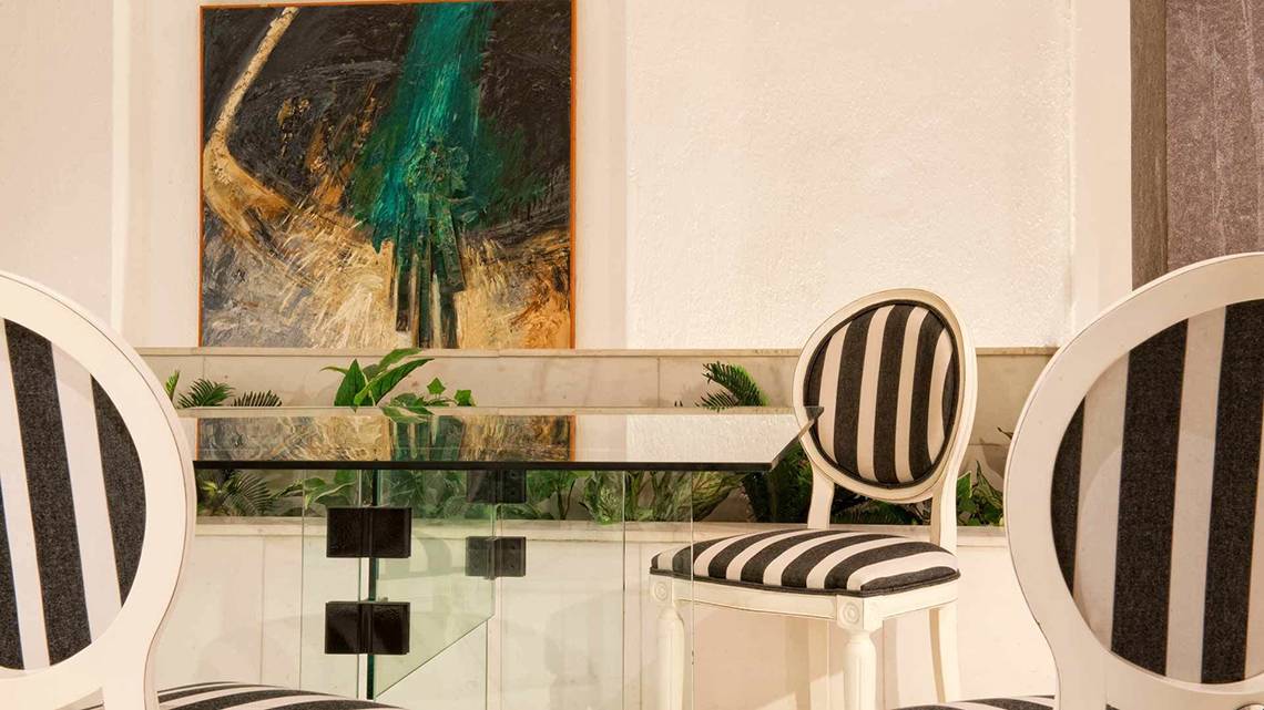Speisebereich im Hersonissos Palace mit modernen Stühlen und Glastisch, vor einer abstrakten Wandmalerei.