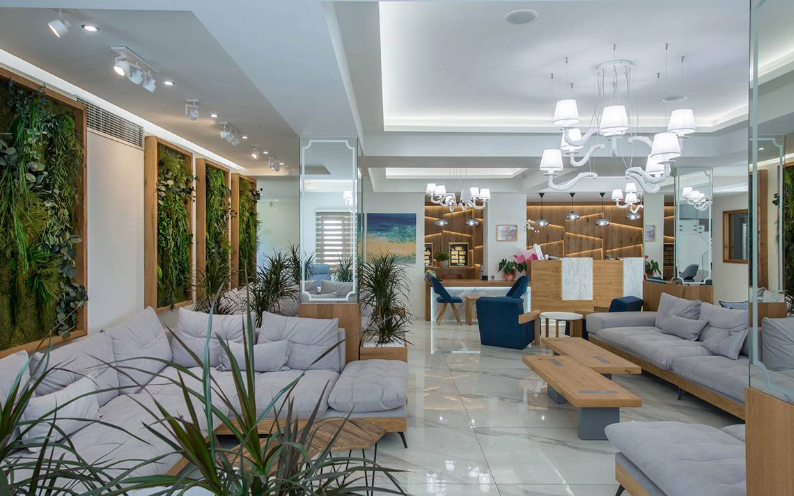 Lobby des Odyssia Beach Hotels mit Sofas, Pflanzen und einer Rezeption.