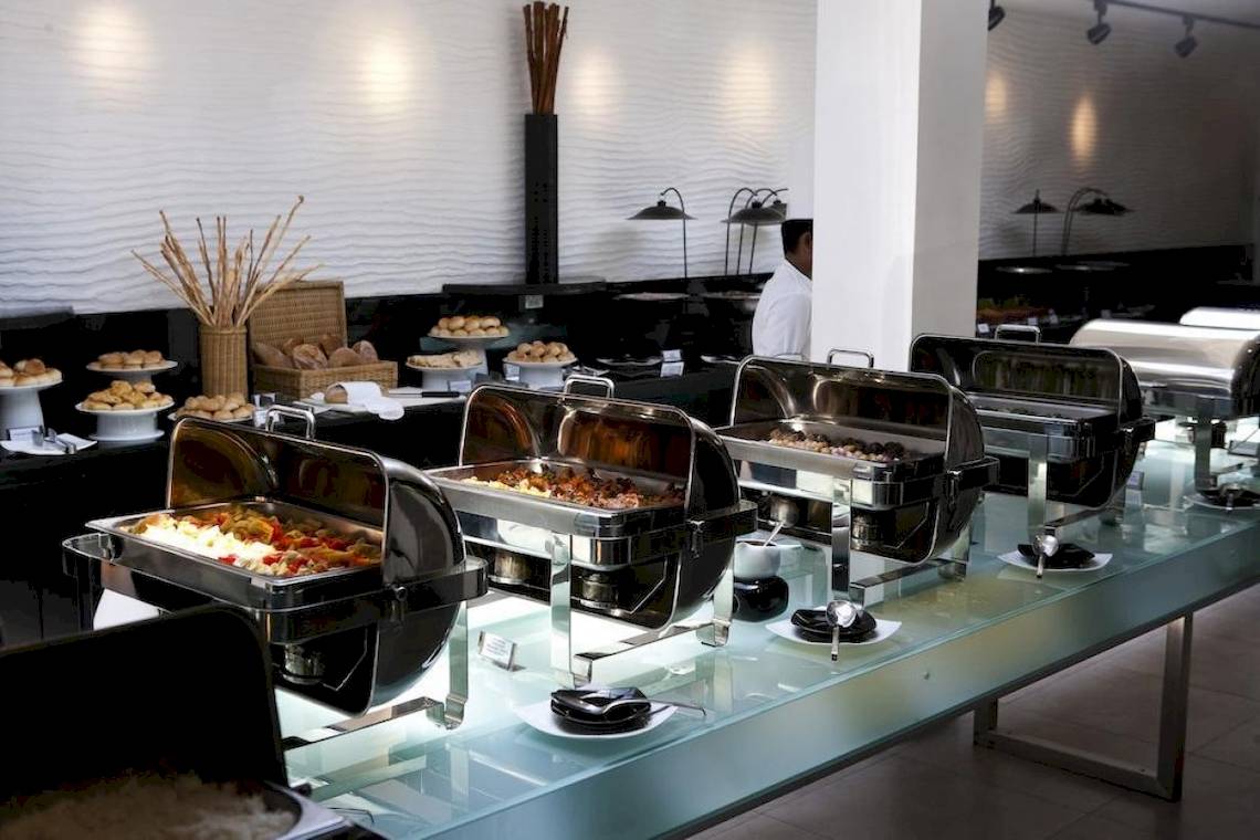 Buffet-Setup im Club Hotel Dolphin mit verschiedenen Speisen in Silberschalen auf einer Glastheke.