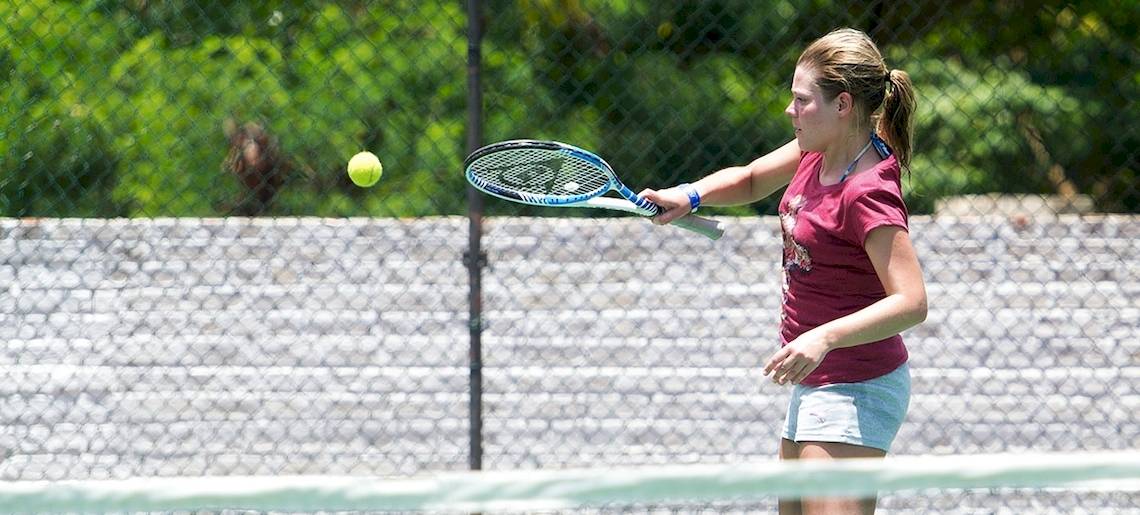 Junge Frau spielt Tennis auf einem Tennisplatz im Club Hotel Dolphin.