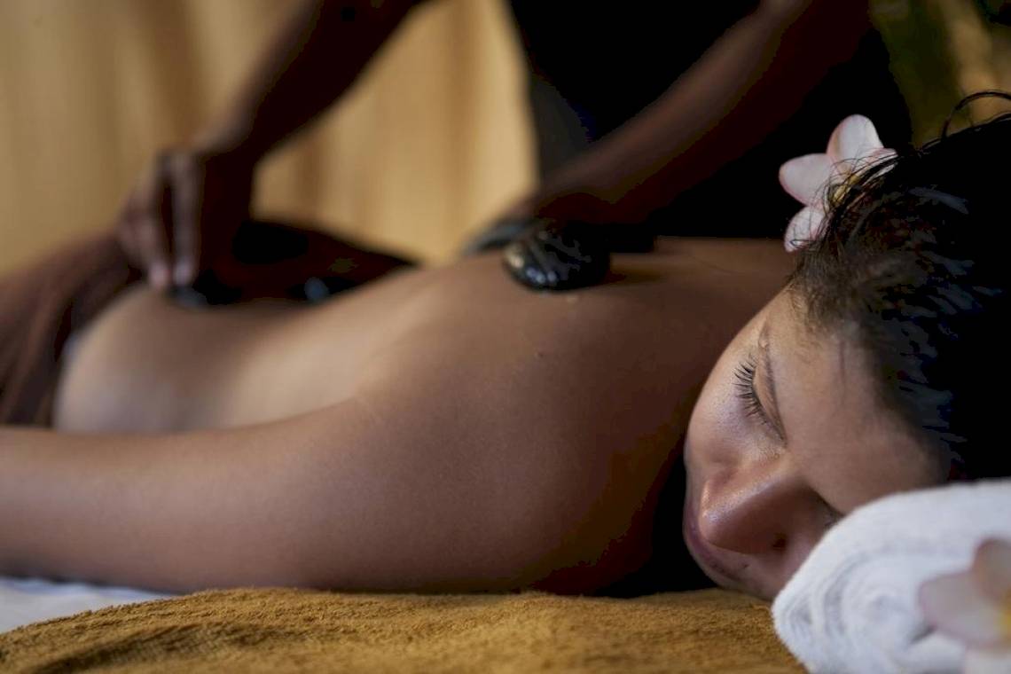 Frau genießt Massage im Club Hotel Dolphin mit Blumen und Hand in Rücken