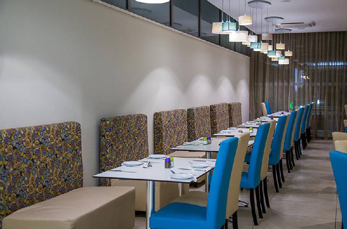 Innenansicht des Restaurants im Stamatia Hotel mit blauen Stühlen und gemusterten Sitzbänken.