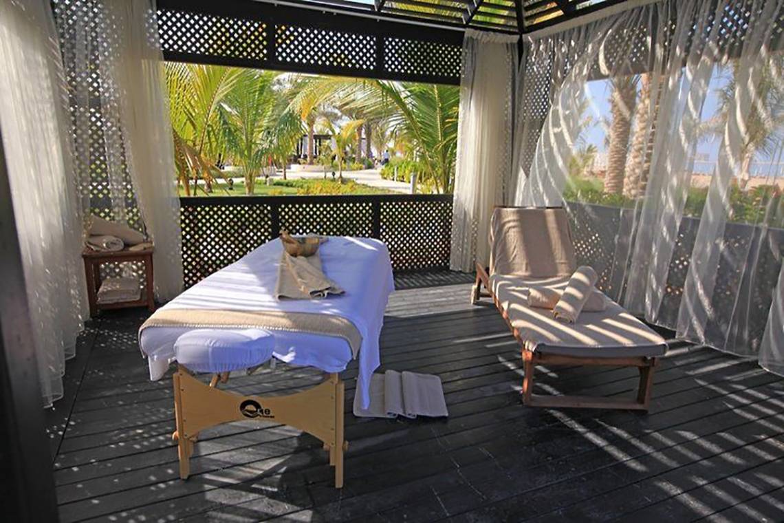 Spa-Bereich im Freien im Waldorf Astoria Ras Al Khaimah mit Massageliege und Sonnenliegen.