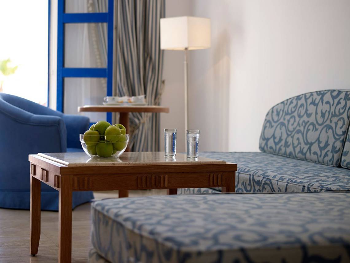 Hotelzimmer des Mitsis Norida Beach mit Couch, Tisch, Lamp und Obstschale
