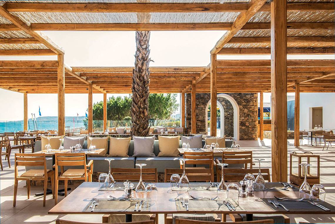 Terrasse im Mitsis Norida Beach Hotel mit Blick auf das Meer und Palmen.