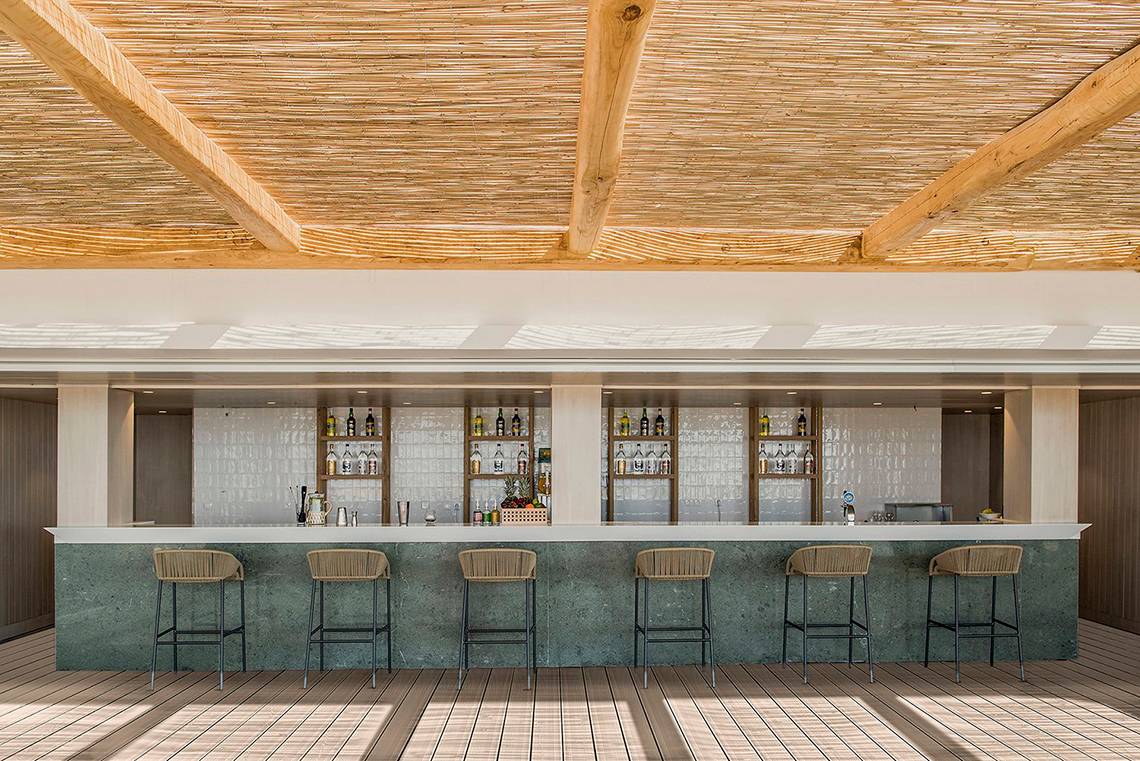 Bar-Terrasse im Mitsis Norida Beach Hotel mit Holzsäulen und Weinfässern.