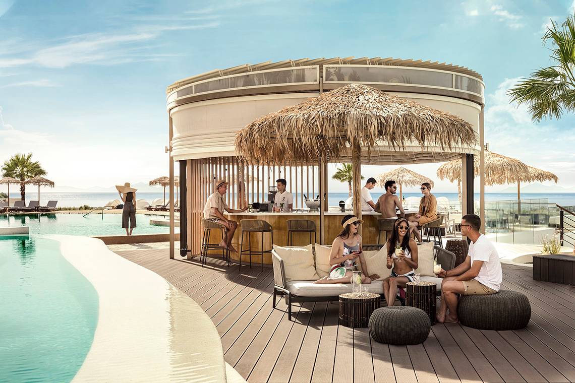 Gäste entspannen an der Terrasse des Mitsis Norida Beach Hotels mit Blick auf das Meer.