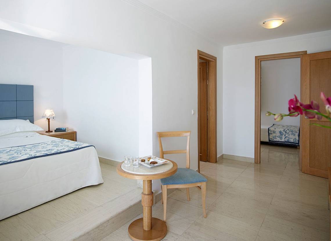 Schlafzimmer im Mitsis Norida Beach Hotel mit Bett, Tisch und Stuhl.