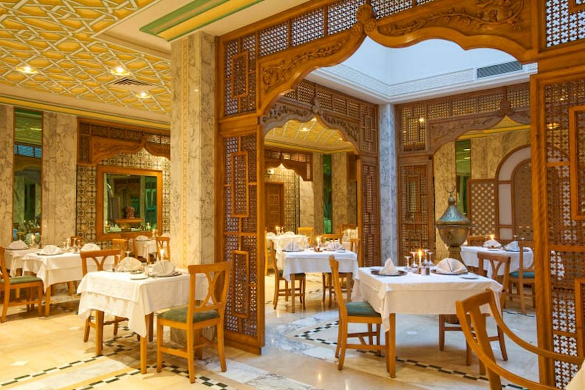 Innenansicht des Restaurants im El Mouradi Mahdia Hotel mit gedeckten Tischen und dekorativen Holzelementen.