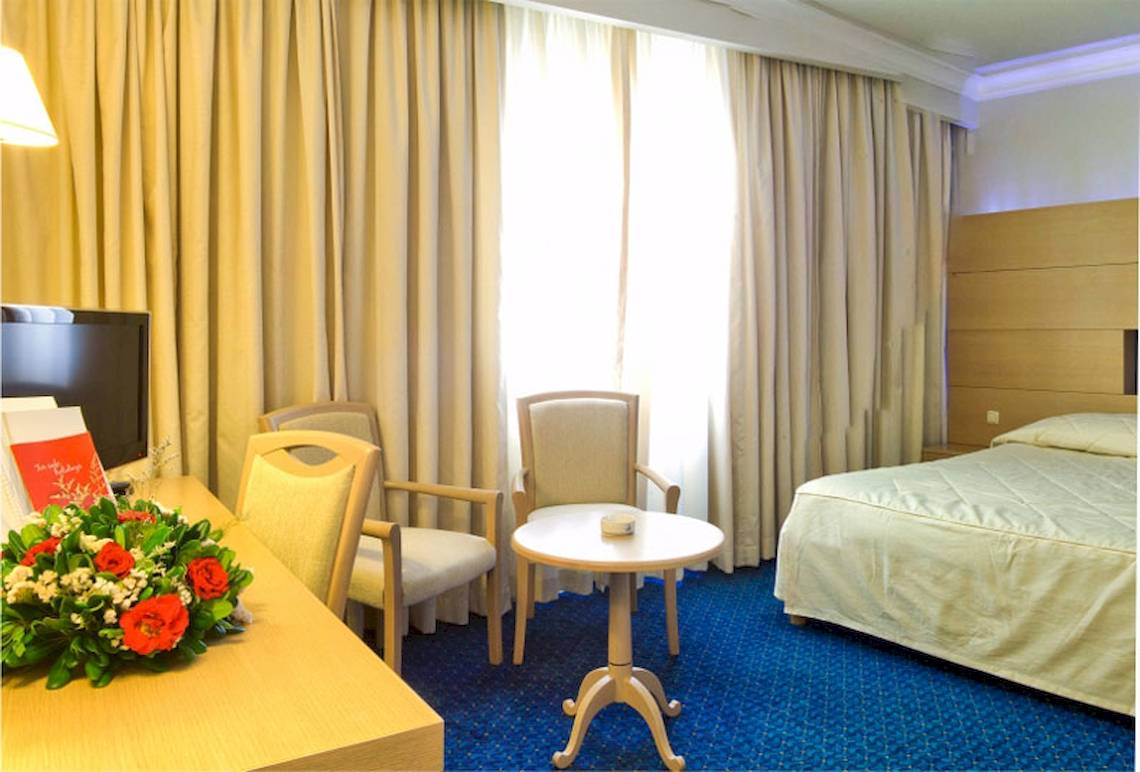 Hotelzimmer im El Mouradi Mahdia mit Bett, Schreibtisch, Stühlen und Blumen.
