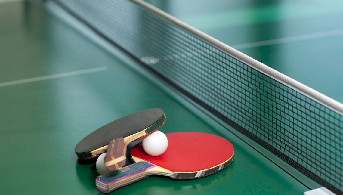 Ping-Pong-Tisch mit Schlägern und Ball auf grüner Oberfläche