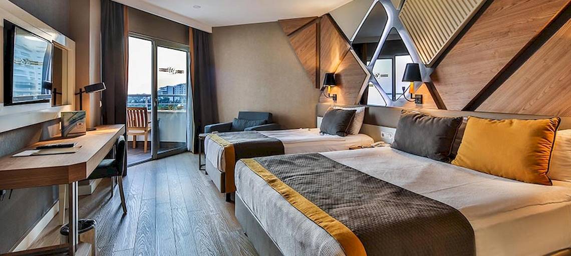 Zwei Betten mit gelben und grauen Kissen in einem modernen Hotelzimmer des Saturn Palace Resort.