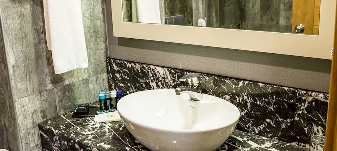 Badezimmer im Saturn Palace Resort mit weißem Waschbecken und Marmorplatte.