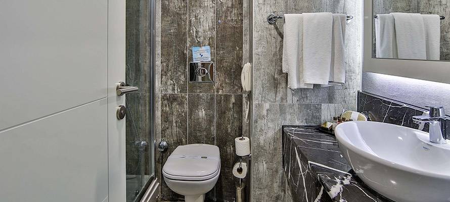Badezimmer im Saturn Palace Resort mit Dusche, Toilette, Waschbecken und Handtüchern.