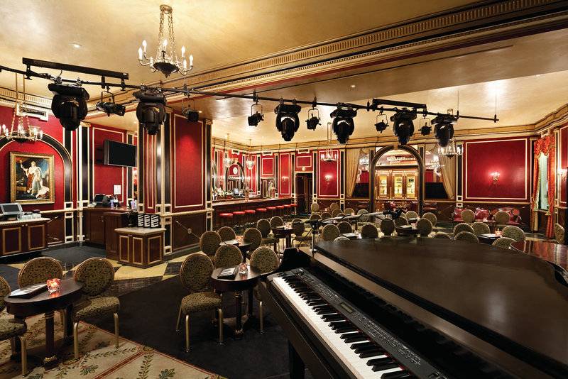 Innenbereich des Paris Las Vegas Hotels mit rotem Dekor, einer großen Klavier, und runden Tischen.