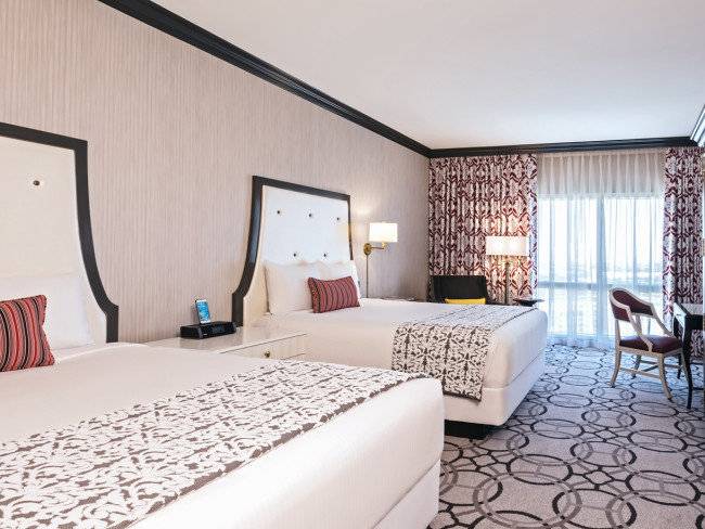 Doppelbett-Zimmer im Paris Las Vegas Hotel mit modernen Dekor, zwei Betten, Nachttischen und Fenstern.