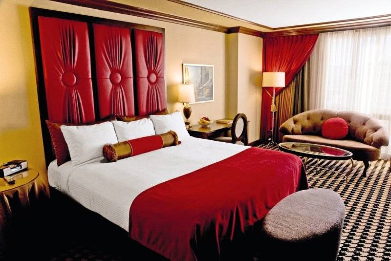 Ein elegantes Hotelzimmer im Paris Las Vegas mit einem großen Bett, rotem Dekor und Möbeln.