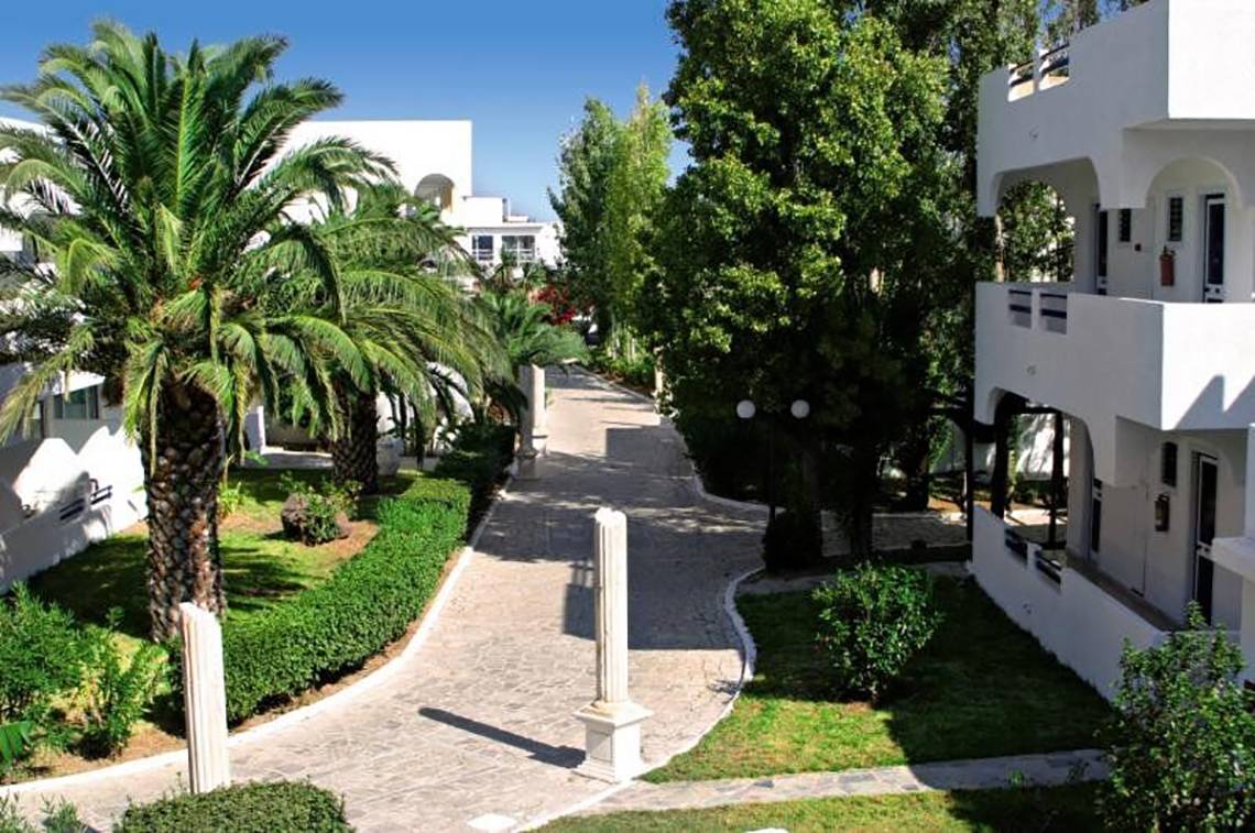 Eingangsbereich des Smy Kos Beach & Splash Hotels mit Palmen und weißen Gebäuden.